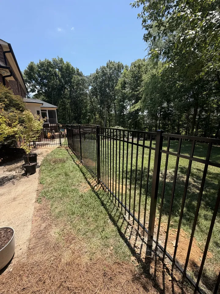 Black aluminum fence along a side yard beside a brick home.