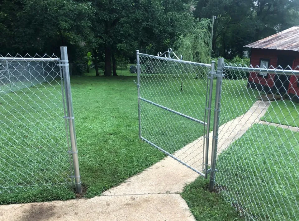 Galvanized chain link double drive gate opened over a concrete walk.