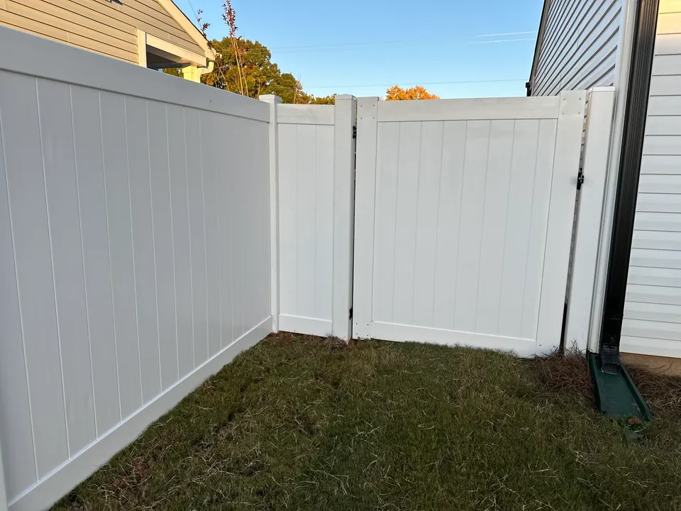 White vinyl privacy gate in a fence corner.
