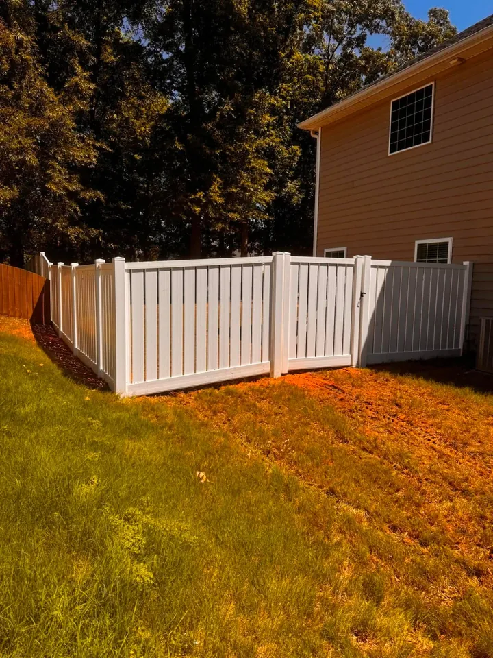 White vinyl semi privacy fence on a sloped backyard.