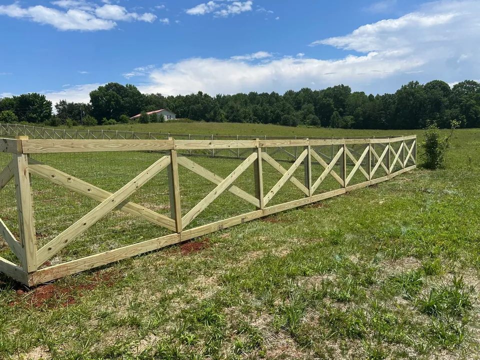 Wood crossbuck farm fence along a pasture.