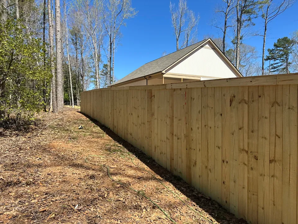 Pressure treated wood privacy fence along a long side yard.
