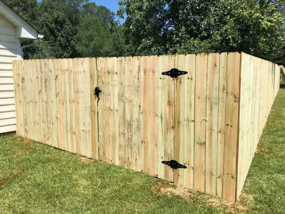 Pressure treated wood privacy fence corner with a walk gate.
