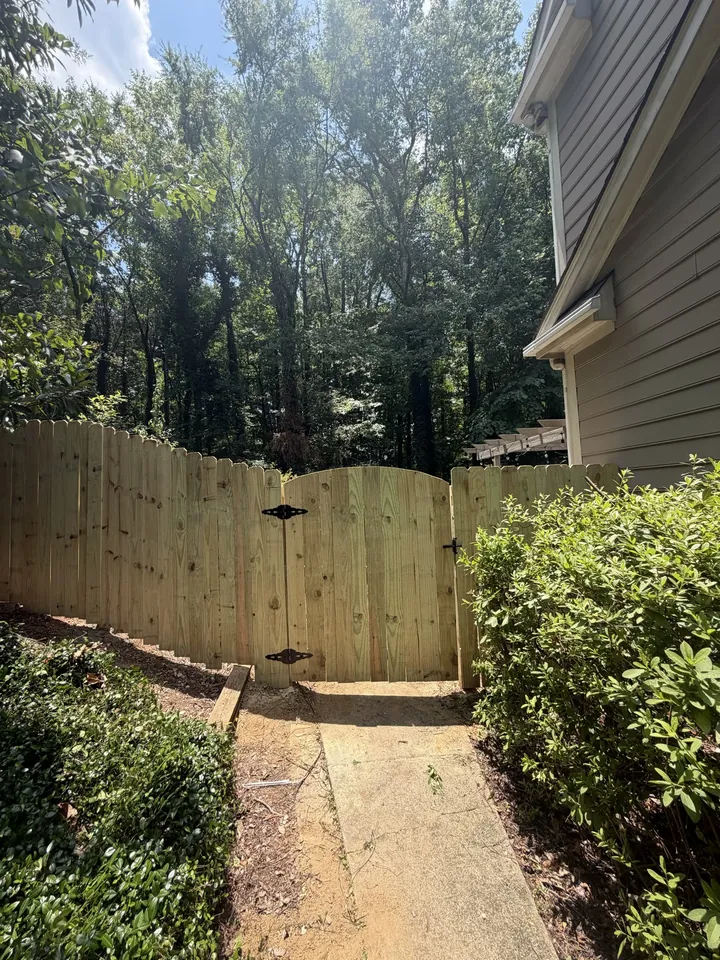 Wood privacy fence and gate along a side walk.